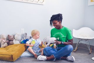 sitter and child playing with stuffed animal